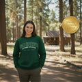Person wearing a green sweatshirt with 'Pali Institute Outdoor Education' text, standing in a forested area.