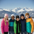 Children in colorful winter jackets standing in front of snow-covered mountains